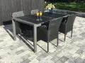 En uteplats med stenläggning, ett mörkt bord med korgstolar och glas med juice.