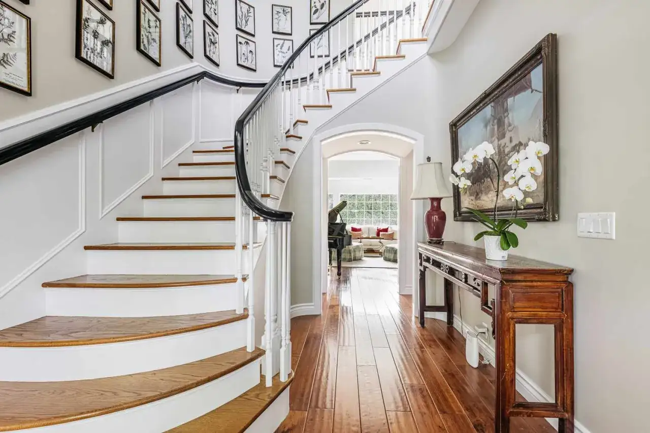 Elegant trappa inomhus inspiration med vit balustrad och mörkt räcke. Konstverk pryder väggen ovanför en antik konsol.